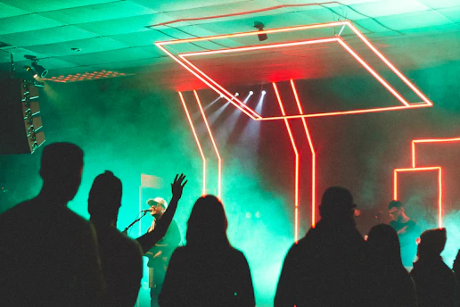 A vibrant neon-lit concert stage with a crowd enjoying the music under dark mode ambiance.