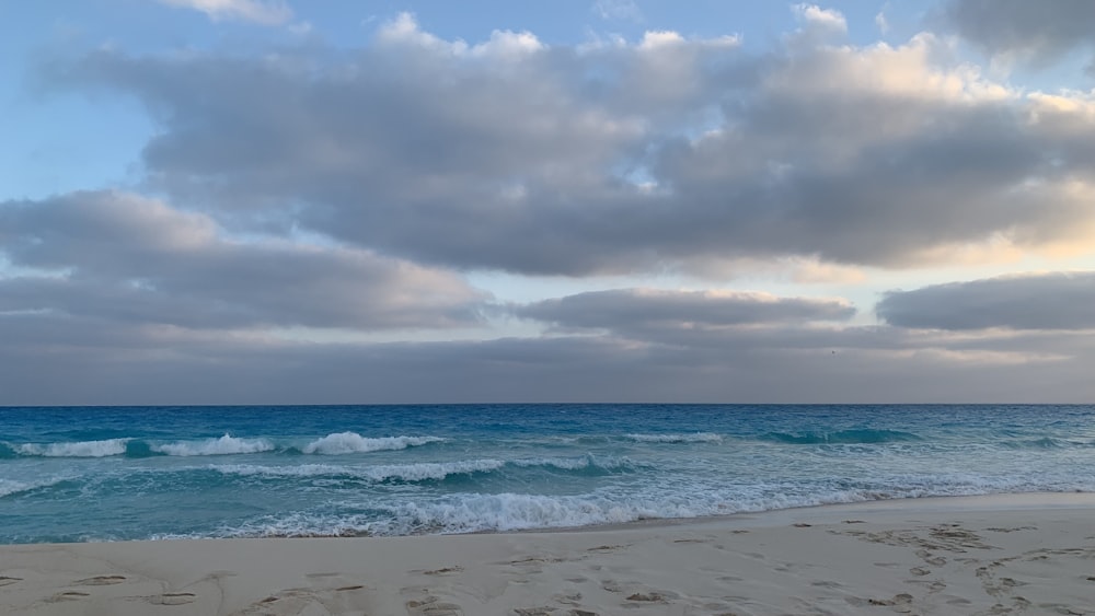 a beach with waves and clouds