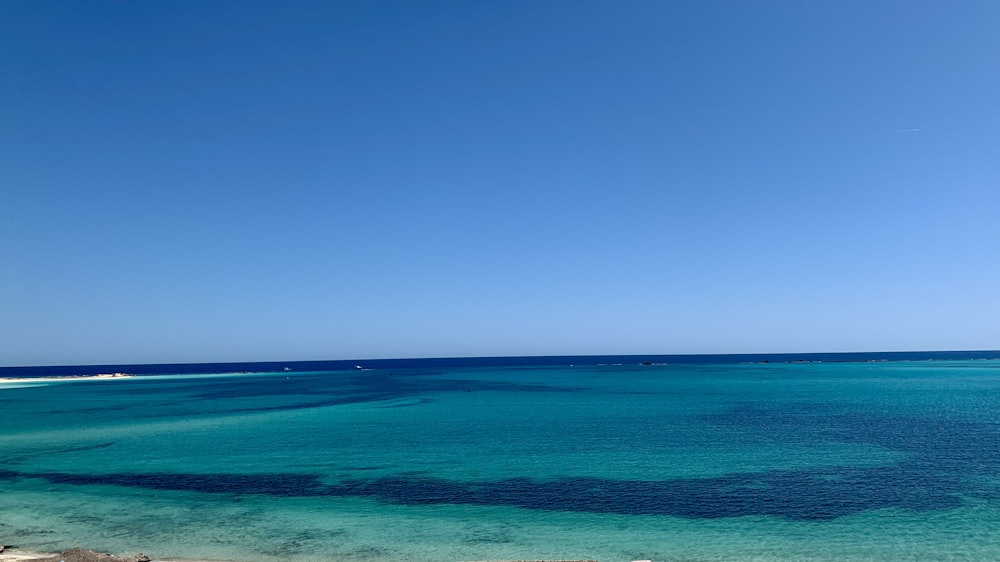 a body of water with a beach and blue sky