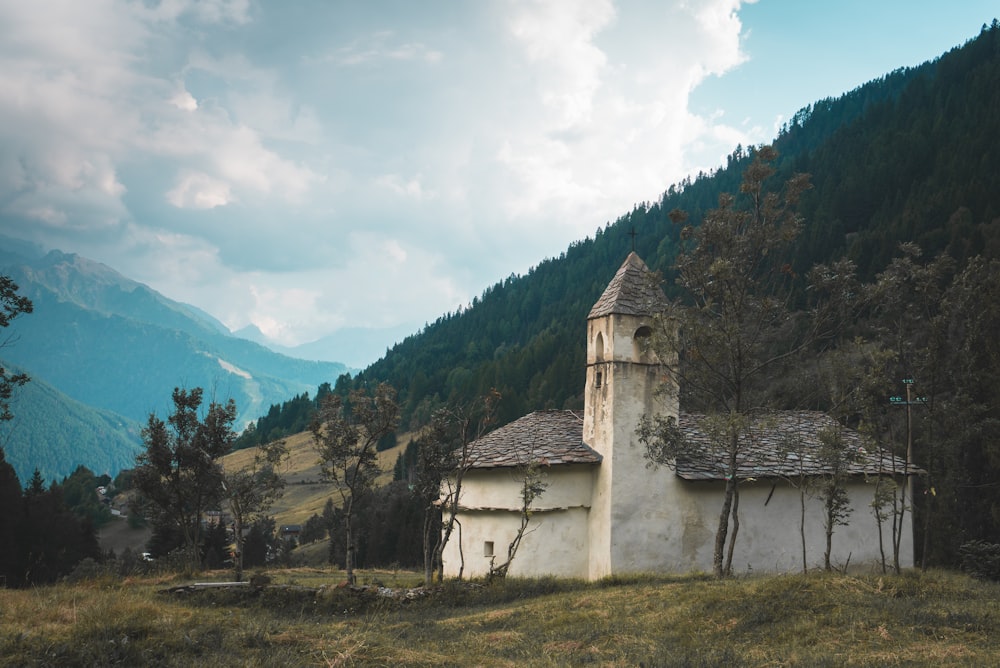 Un bâtiment blanc avec une tour devant une montagne