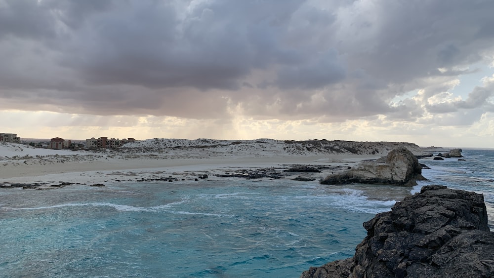 a rocky beach with a town in the distance