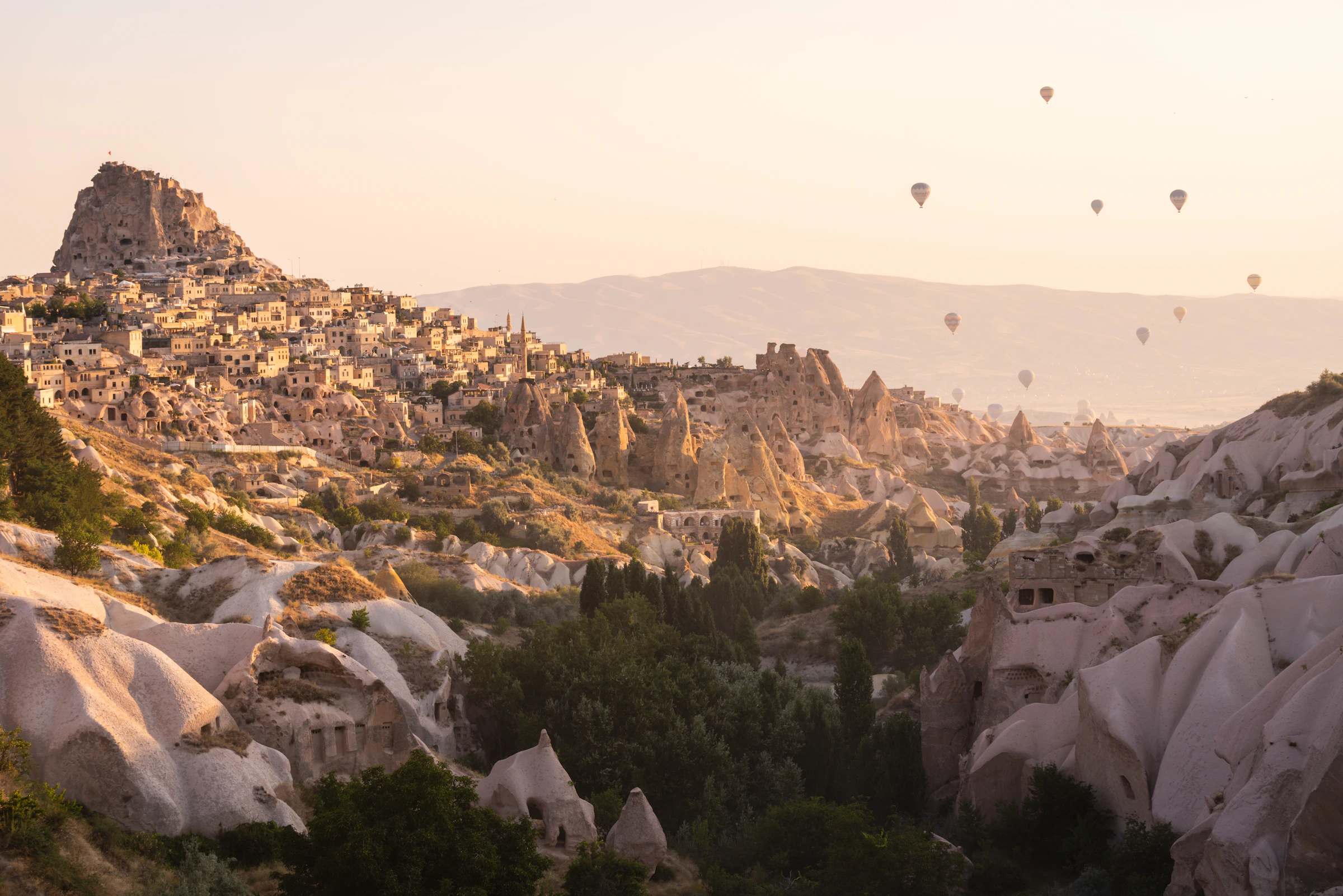 Hot air balloons above the rocky valleys and village of Uchisar in Cappadocia