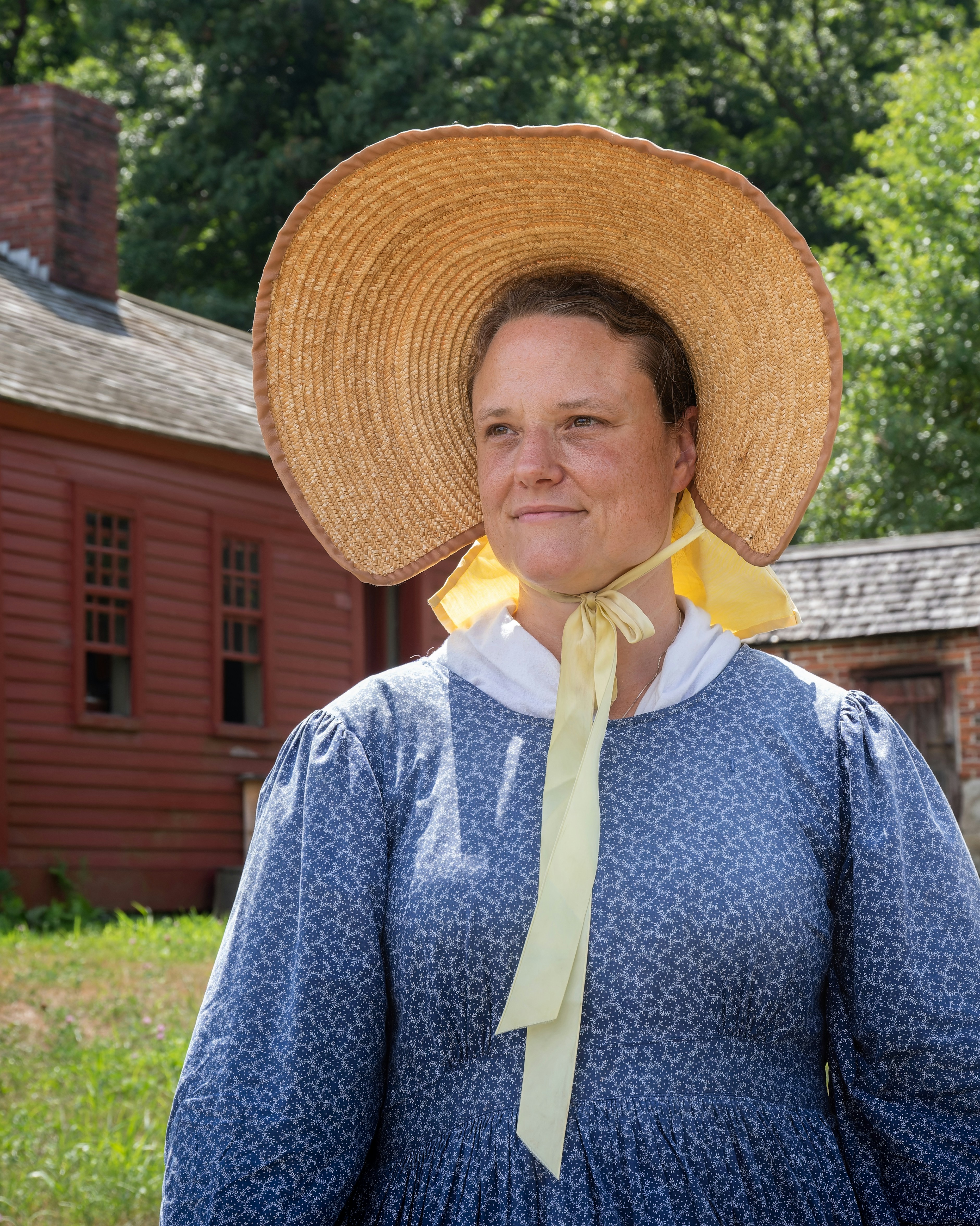 Lady of the era wearing wide brimmed straw bonnet with yellow ribbon (circa 1830) Old Sturbridge Village; Aug. 2022