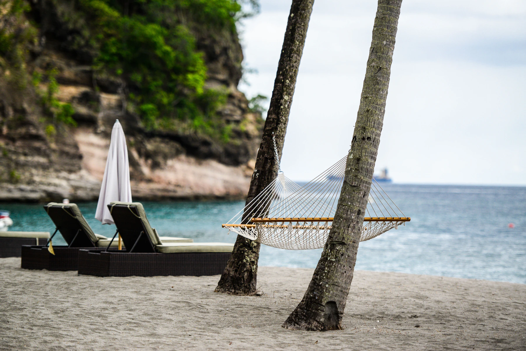 Hammock and outdoor loungers beside a calm tropical beach