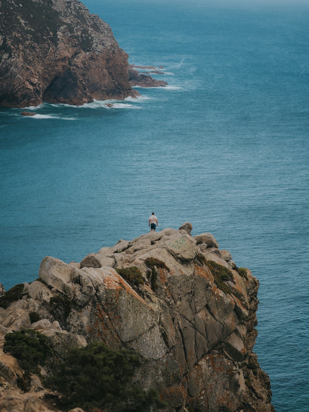 a person standing on a rock above the ocean