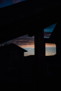 Evening shot capturing the silhouette of a coastal house against a brilliant blue sea and rugged horizon.