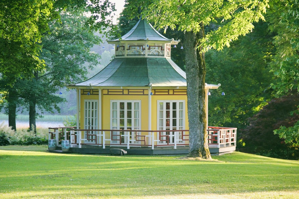 a yellow and white building with a green lawn and trees