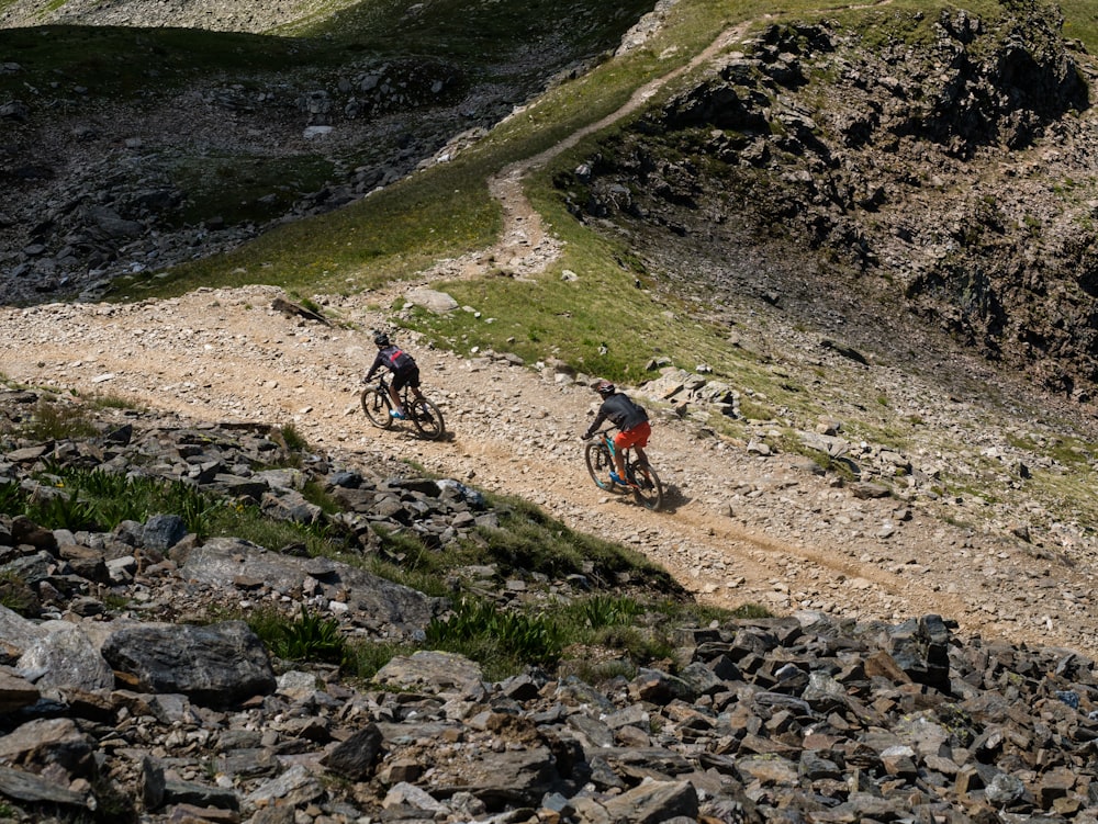 a couple of people riding bikes on a rocky trail