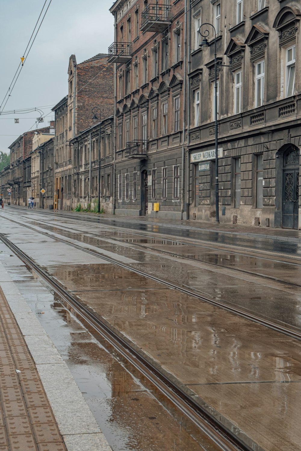 A wet street with buildings on either side of it photo – Free Kraków Image  on Unsplash