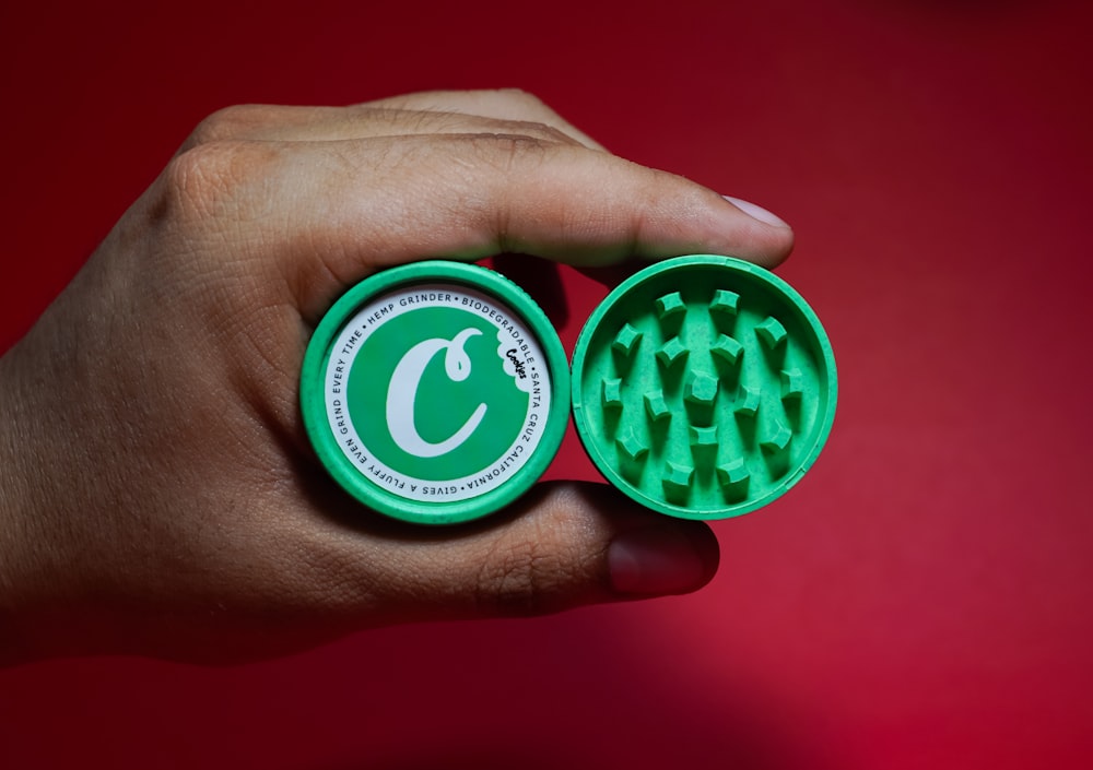 a hand holding a green and white circular object