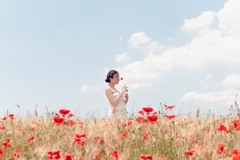 uma pessoa em pé em um campo de flores vermelhas