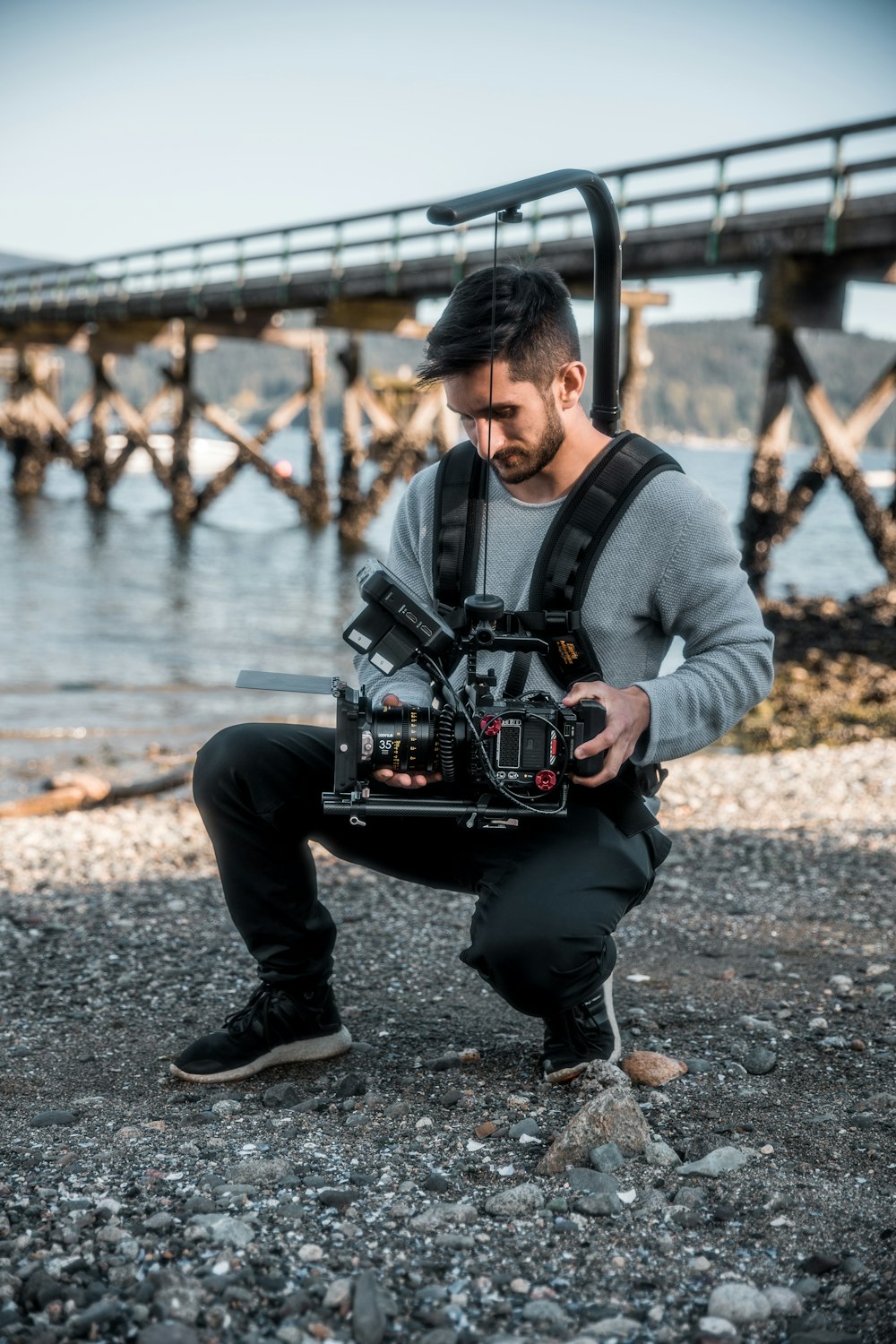 a man kneeling on a rocky shore holding a camera