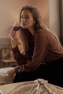Lifestyle shot of a woman enjoying a quiet moment with a glass of wine, surrounded by calm, timeless decor