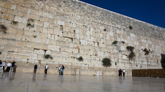 A group of volunteers carefully restoring an old stone wall in a historic village.