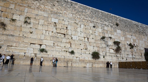 A group of volunteers carefully restoring an old stone wall in a historic village.