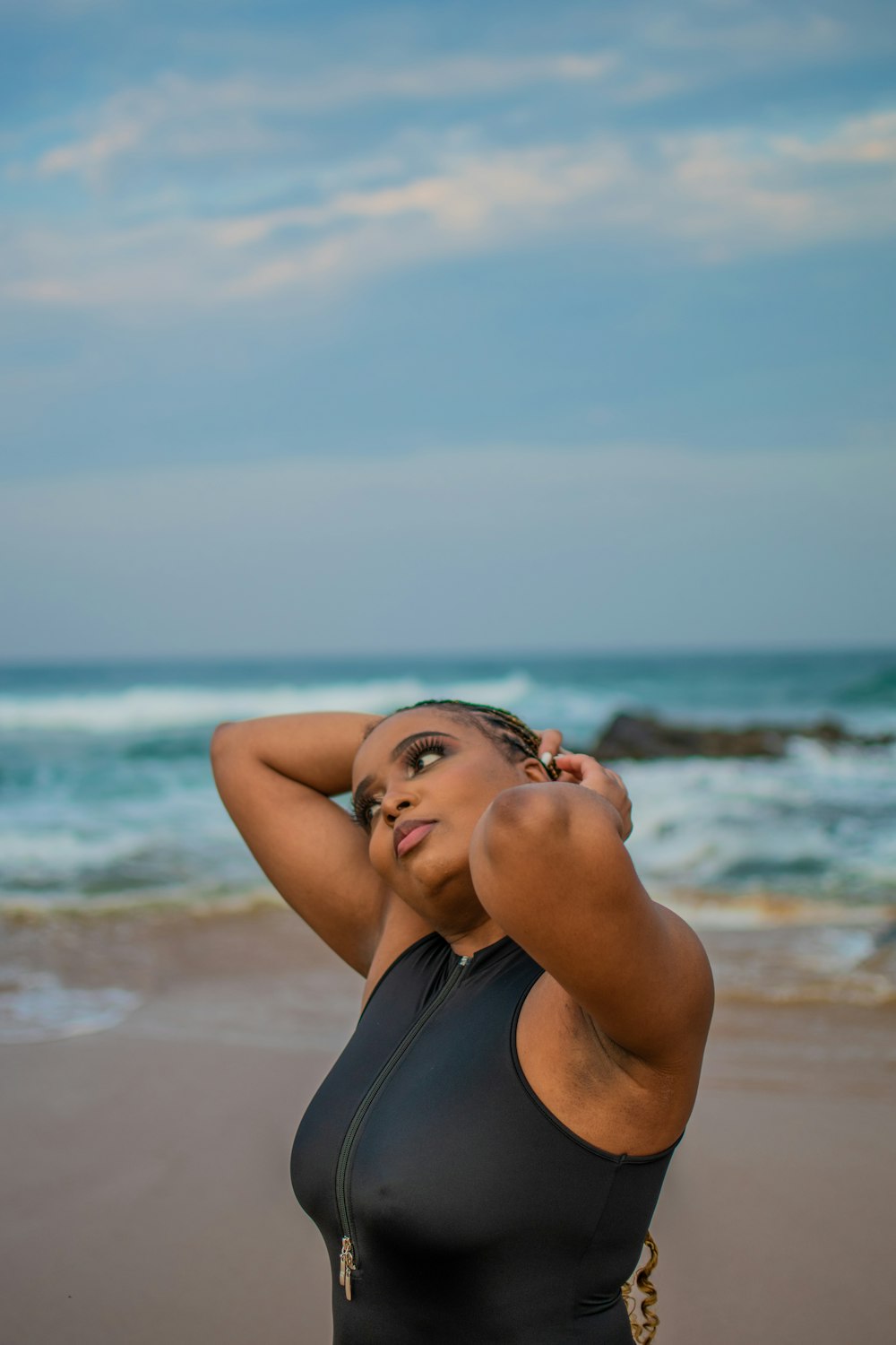 a woman with her hands on her head on a beach