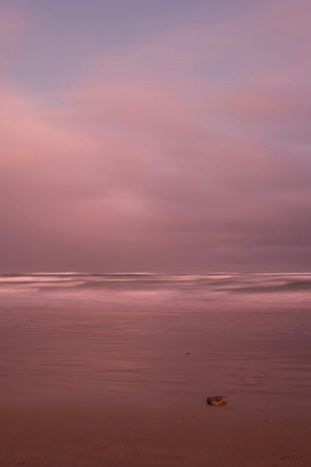 a beach with a pink and purple sky