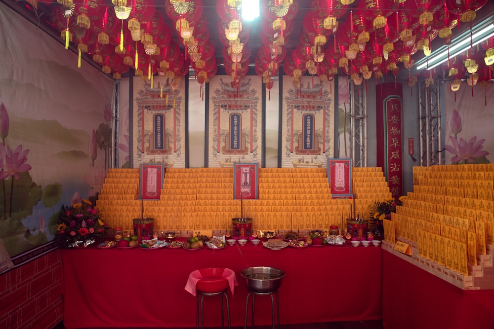 a room with a red table and red tablecloths and a wall with art on it