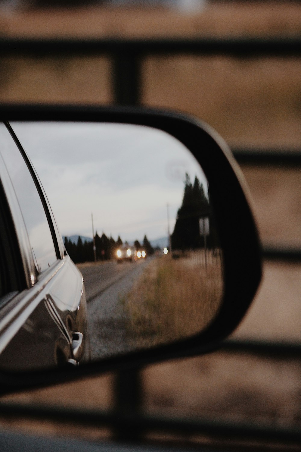 a car mirror showing a road and houses