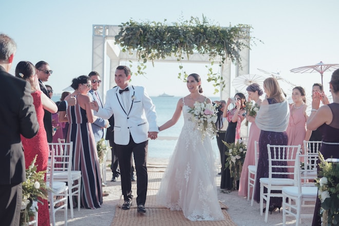 Wedding ceremony with couple walking down beach aisle