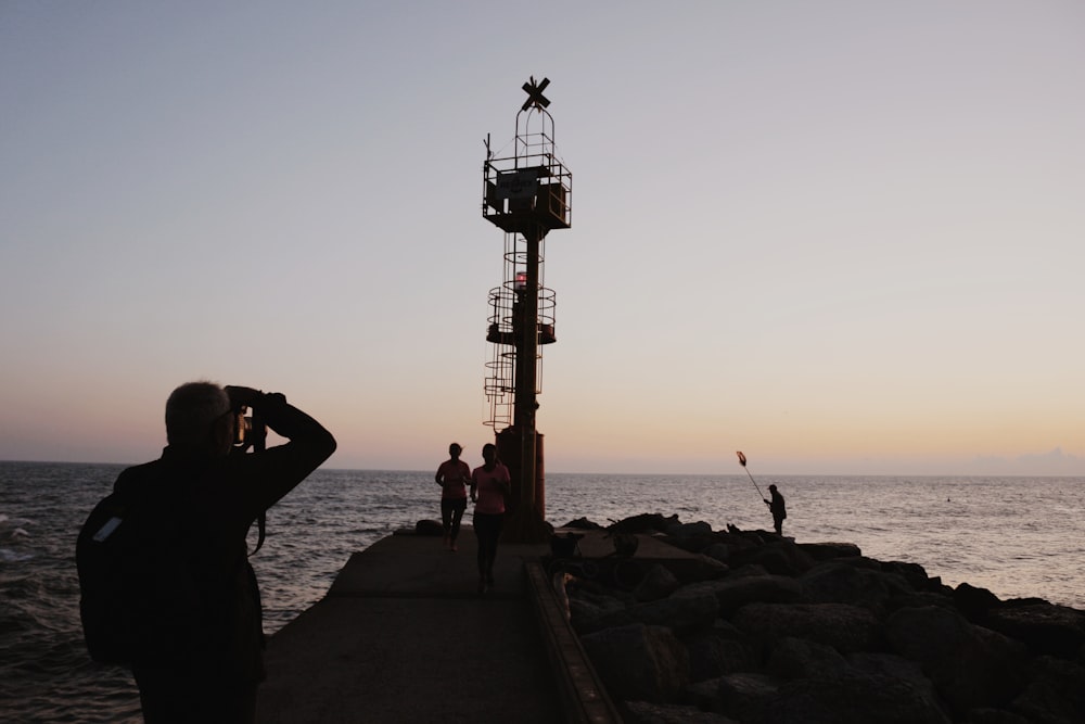 a person taking a picture of a tower on a rocky beach