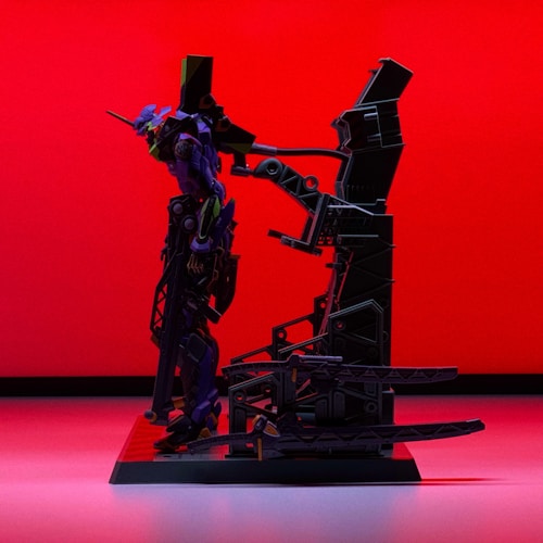 A model of a futuristic robot with sleek design and intricate details stands on a platform against a bold red background. The robot features purple and green accents and appears to be equipped with mechanical components and armor.