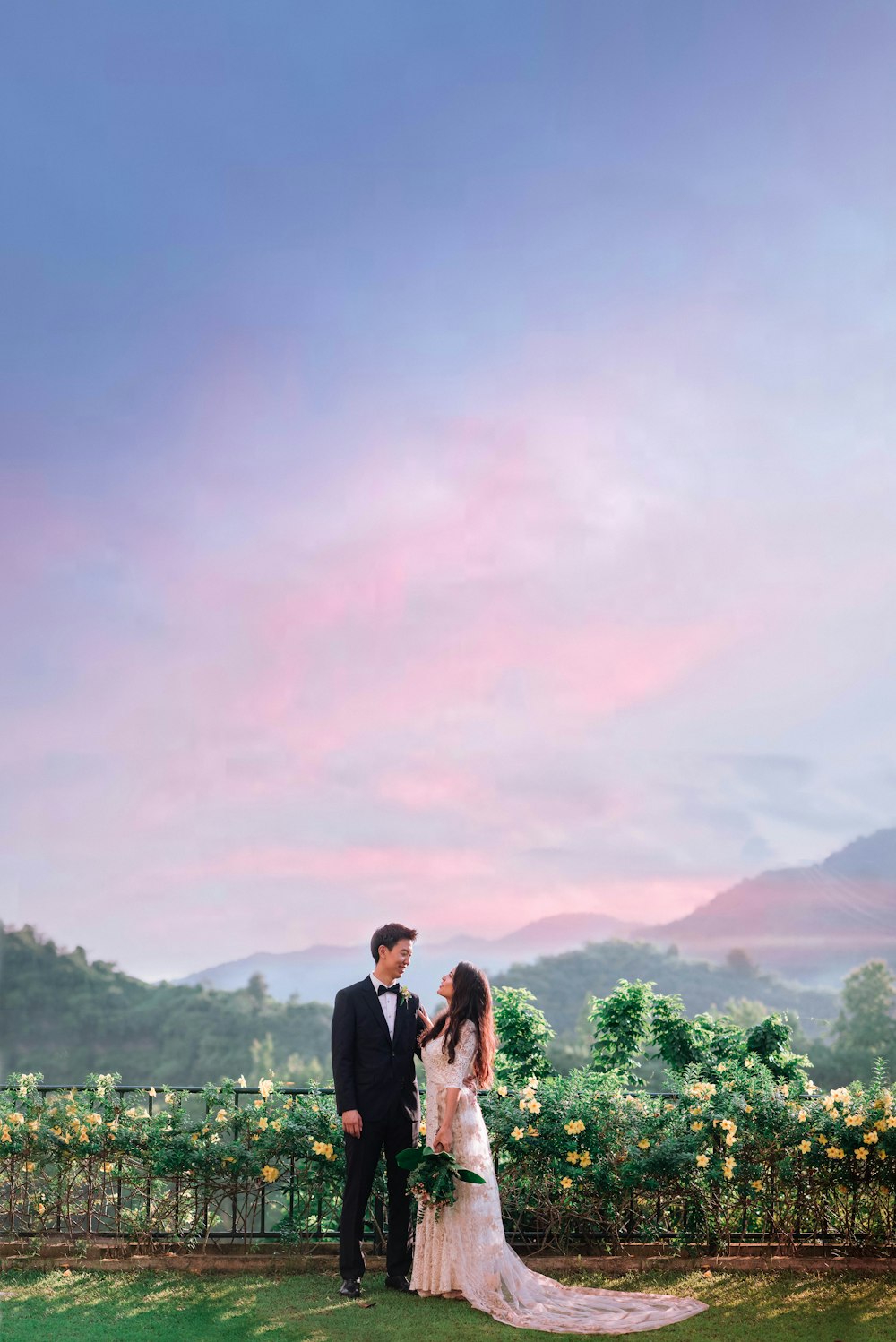 a man and woman in wedding attire standing in front of a vineyard