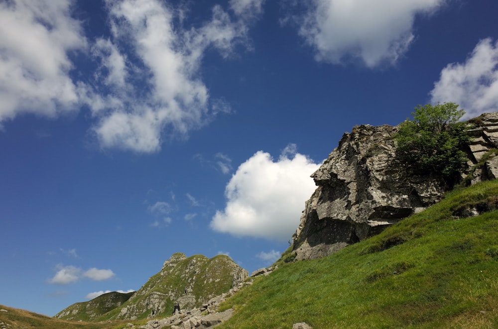 a grassy hill with a rock formation