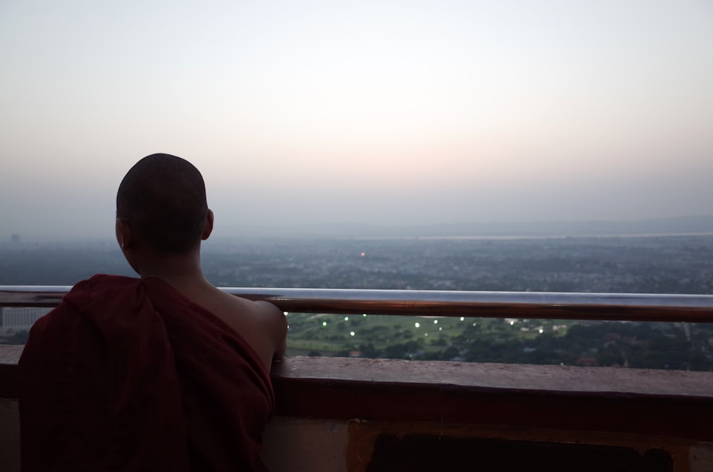 a man sitting on a balcony overlooking a city