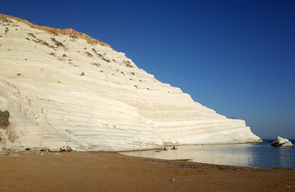 a large sand dune next to a body of water