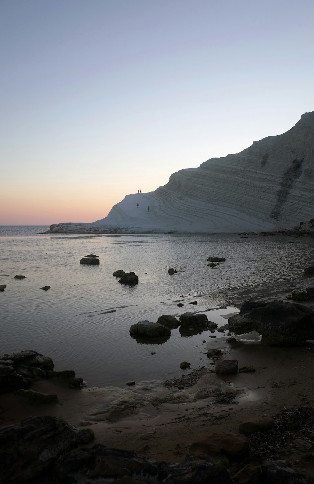 a rocky beach with a hill in the background