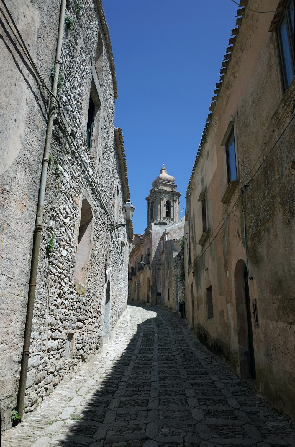 a cobblestone street between two stone buildings
