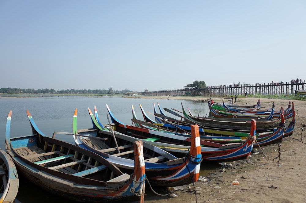 a group of boats sit on the shore of a lake