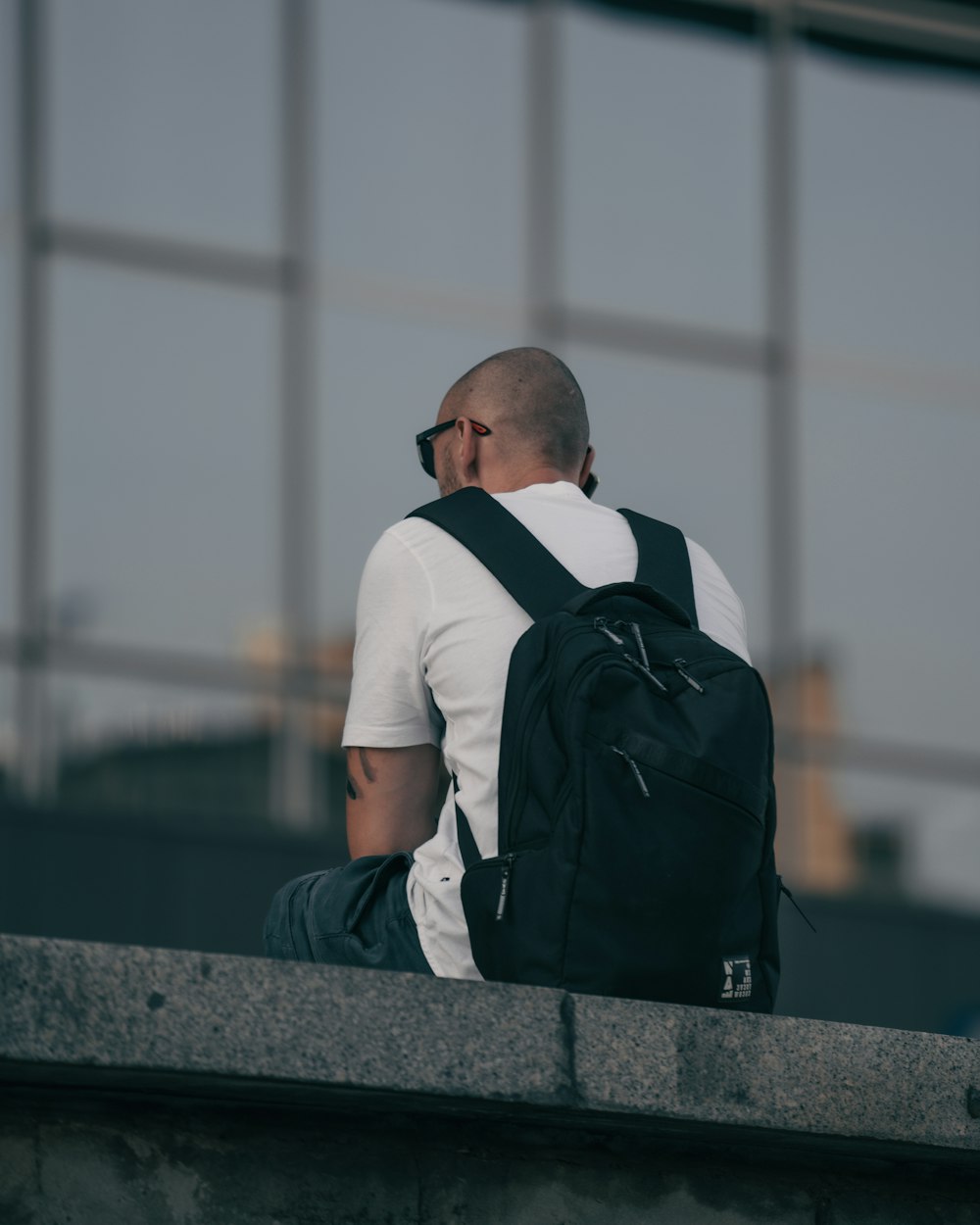 a man sitting on a ledge with a backpack