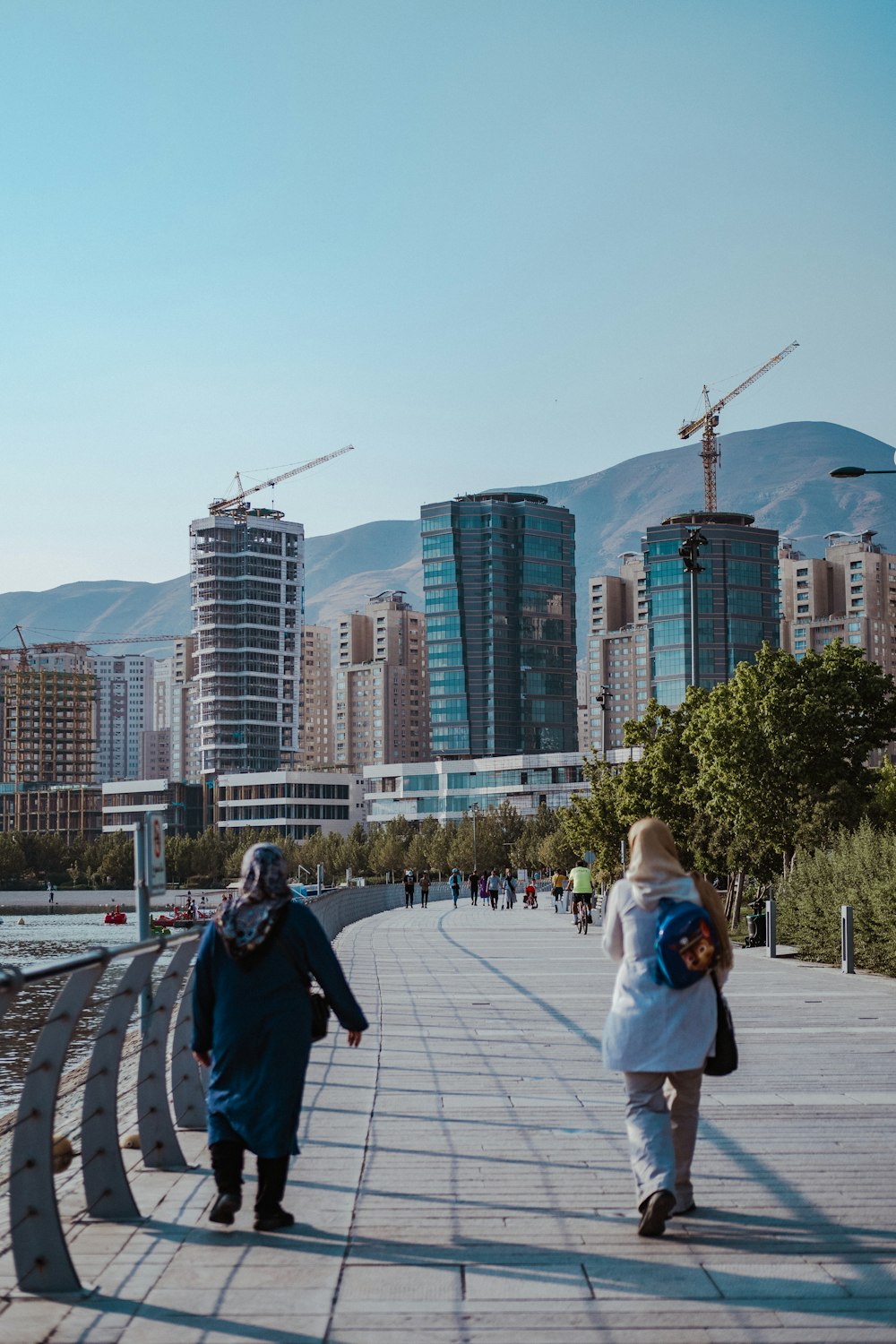 a couple of people walking on a bridge with a city in the background