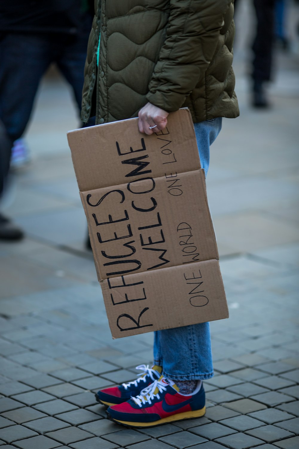 a person holding a cardboard sign on a sidewalk