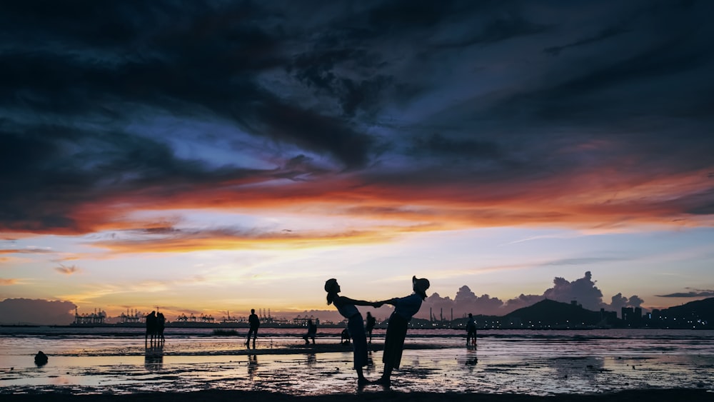 a group of people playing in the water at sunset
