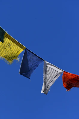 Colorful flags fluttering in the breeze against a clear blue sky.