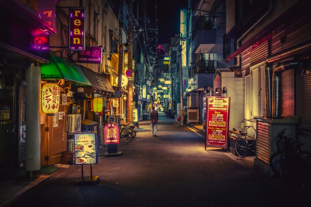 a person riding a bicycle down a street lined with shops