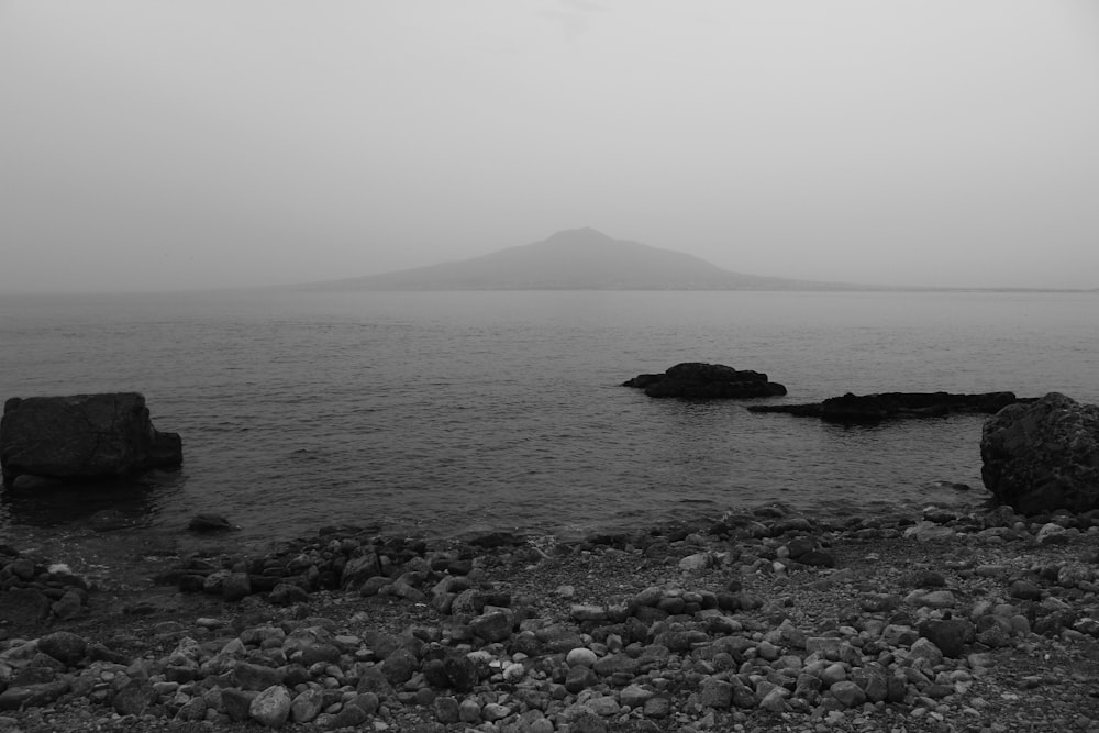 a rocky beach with a large body of water in the background