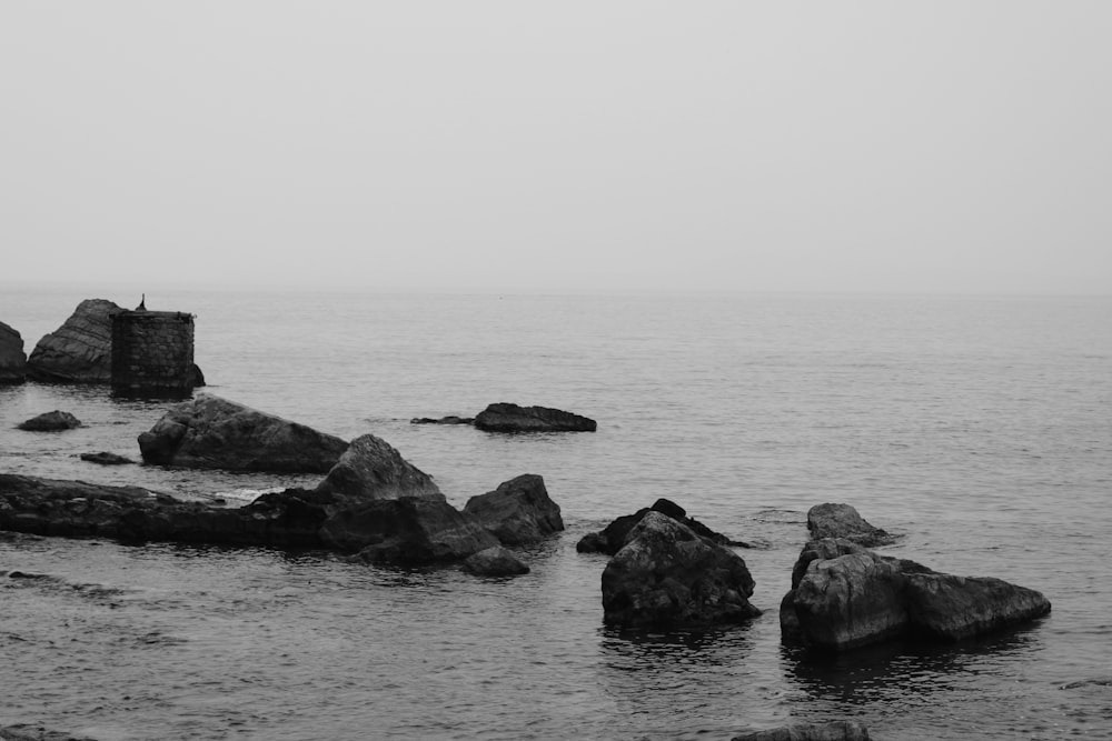 a rocky beach with a person standing on a rock in the water