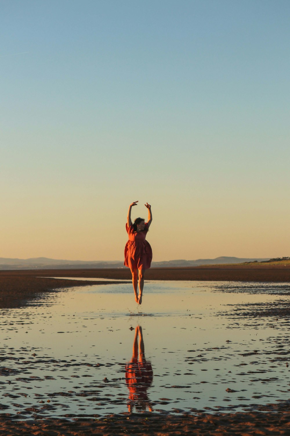 a woman in a red dress is running on the beach