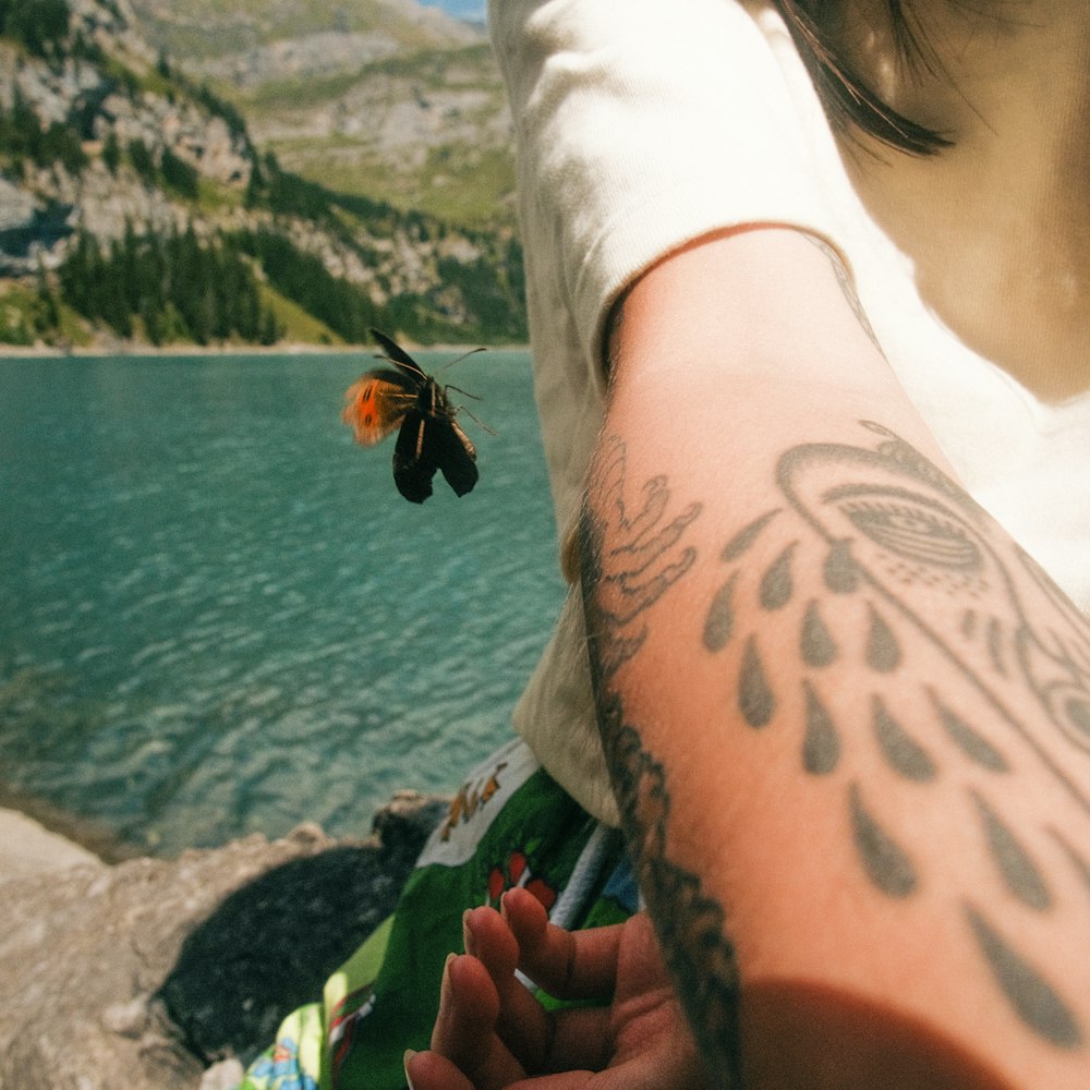 una persona con un tatuaje en el brazo junto a un cuerpo de agua