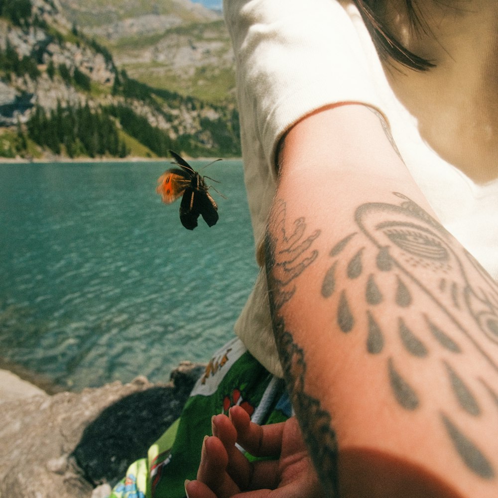 a person with a tattoo on the arm by a body of water