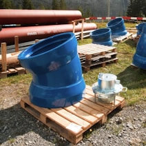 a group of blue and orange water tanks on a wooden bench