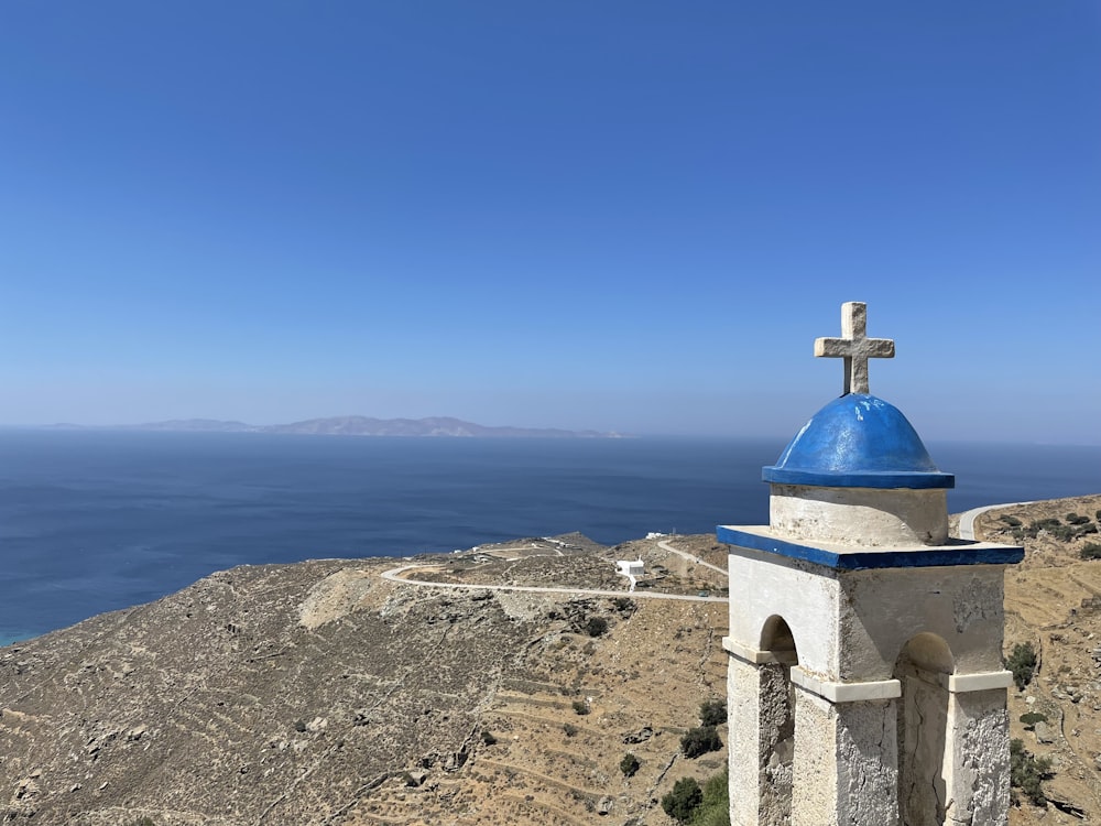 a cross on a stone tower overlooking a body of water