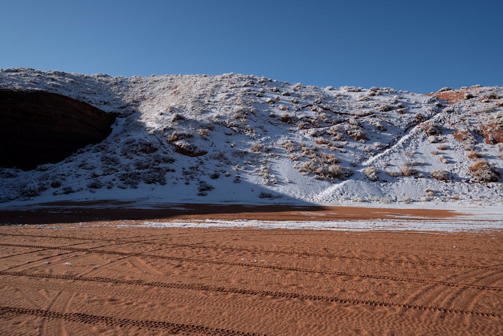 a snowy mountain with a body of water in the foreground