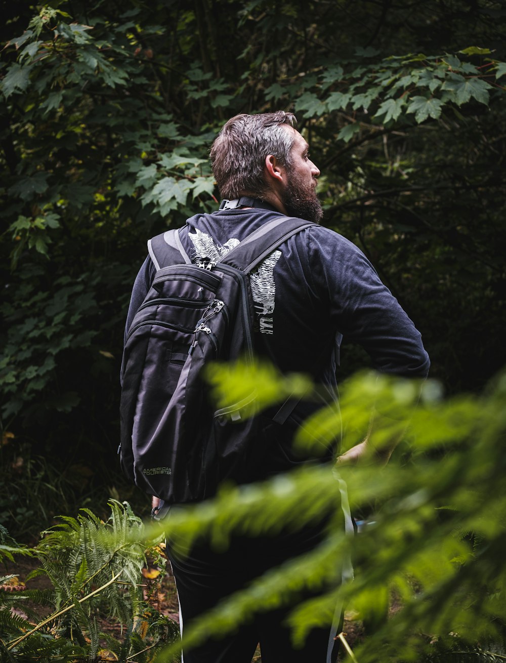 Un hombre con barba mirando un árbol