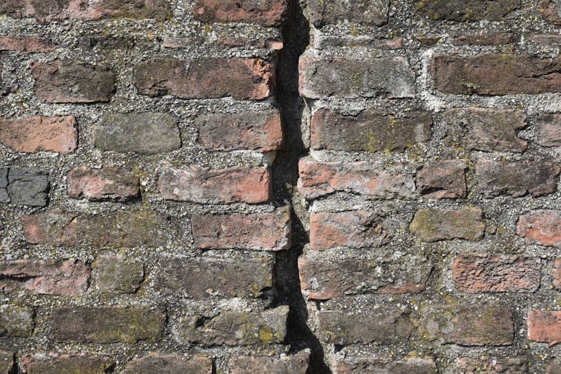A close-up of weathered colonial-era bricks with moss growing between the cracks, capturing the texture of time.