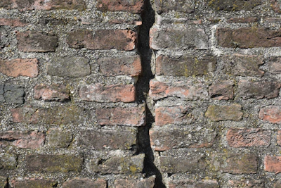 Close-up of a brick wall showing a stepped crack running diagonally.